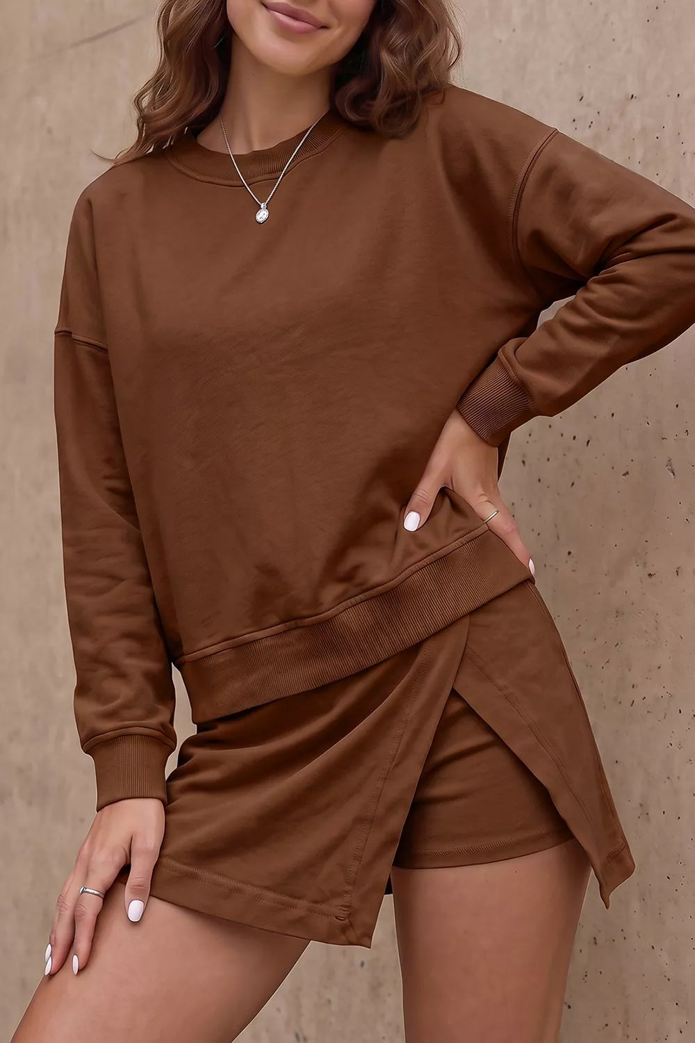 Women's two-piece casual outfit with relaxed long-sleeve crew neck sweatshirt and matching split-front mini skort with built-in shorts.