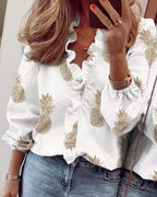 Women's white V-neck ruffle blouse with tan pineapple print, button-front design and gathered sleeves