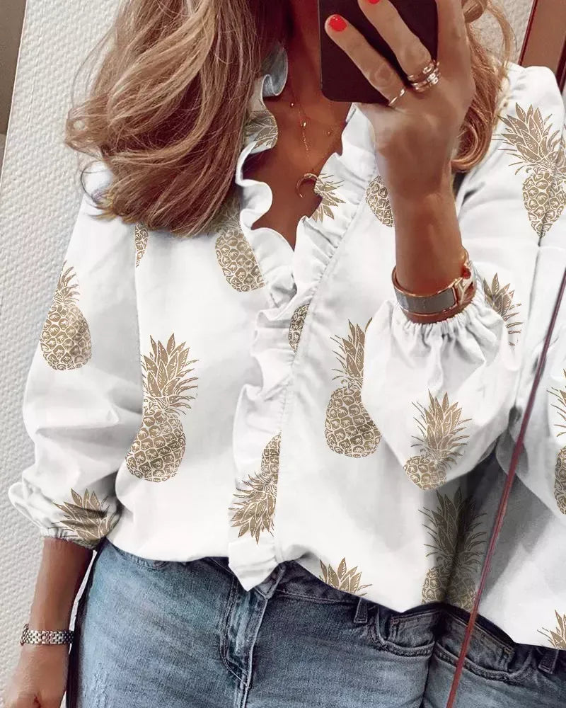 Women's white V-neck ruffle blouse with tan pineapple print, button-front design and gathered sleeves