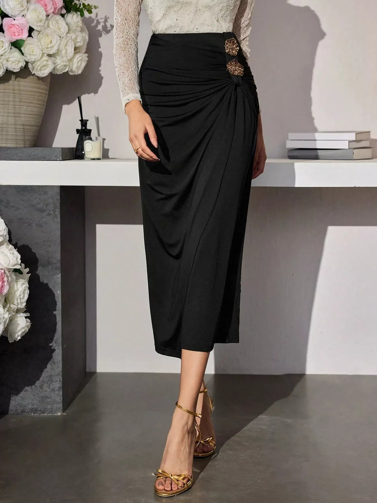 Women's black high-waisted ruched midi skirt with asymmetrical draping and two gold-tone decorative buttons.