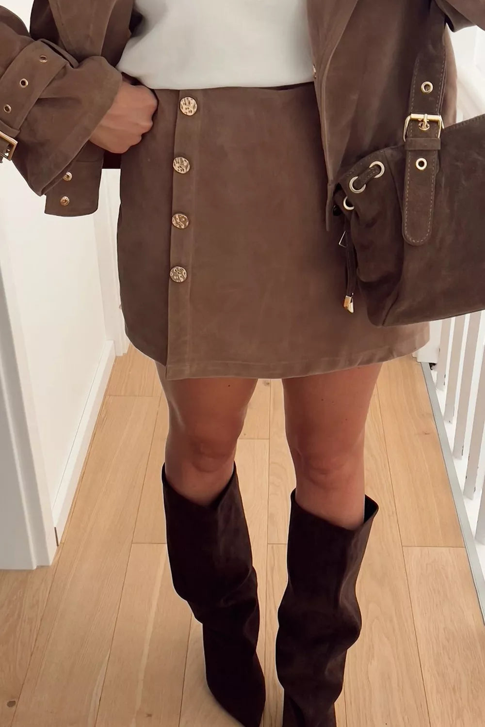 Women's brown button-front mini skort with decorative gold-tone buttons, wrap-style front and skirt-over-shorts design.